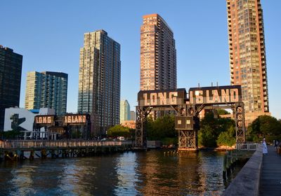 Modern buildings by river against sky in city