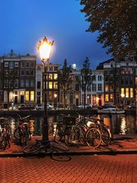 Illuminated buildings by street against sky at dusk