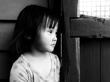 Portrait of cute girl looking away while standing against window