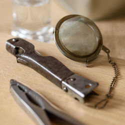 High angle view of pliers and tea strainer on wooden table