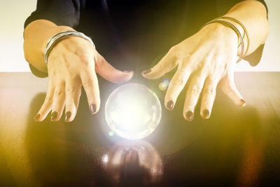 Close-up of hand holding crystal ball on table