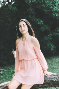 Portrait of young woman sitting on tree trunk