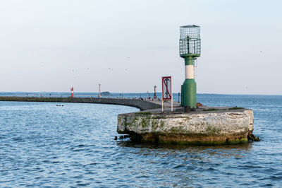 Lighthouse on sea against clear sky