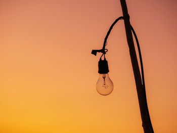 Low angle view of silhouette rope against orange sky