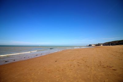 Scenic view of beach against clear blue sky
