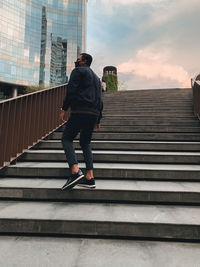 Low angle view of man on staircase in city against sky