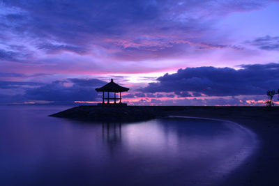 Silhouette built structure by sea against sky at sunset