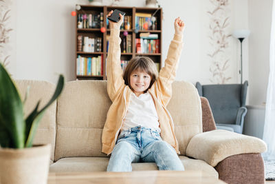 Portrait of boy sitting on sofa at home