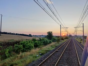 Railroad tracks against sky during sunset