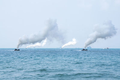 Smoke emitting from sea against sky