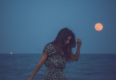 Woman standing in sea against clear sky