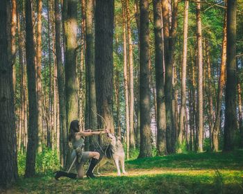 Woman standing on tree trunk in forest