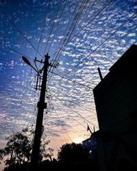 Low angle view of silhouette tree and building against sky