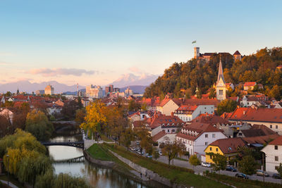 Town by river and buildings in city against sky