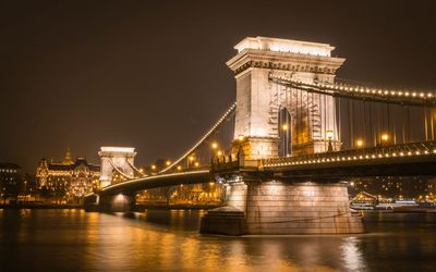 Illuminated suspension bridge over river at night