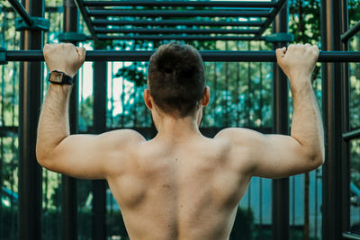 Rear view of shirtless man looking at camera