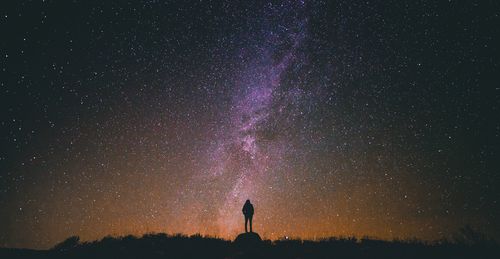 Low angle view of woman standing against star field at night