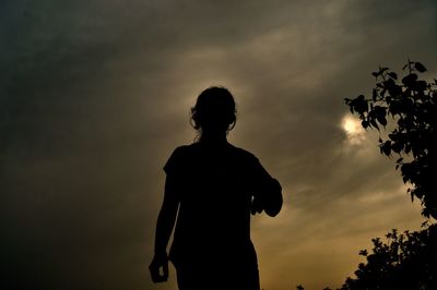 Silhouette woman standing against sky during sunset