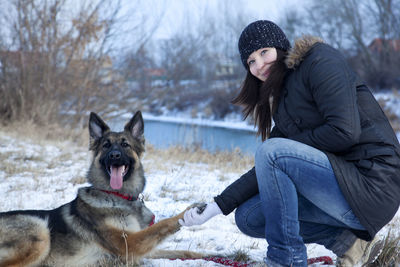 Portrait of woman with dog on land during winter