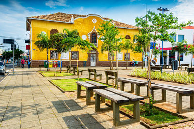 Park bench by building against sky