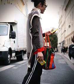 Side view of young man standing in city