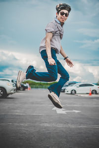 Full length of man jumping on road against sky