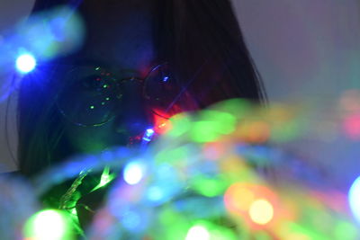 Close-up portrait of woman with illuminated lights at night