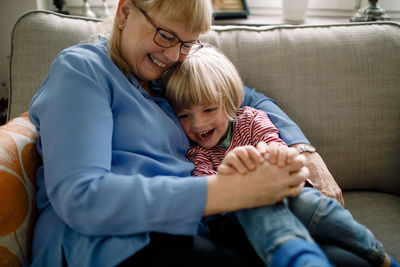 Happy boy sitting with grandmother on sofa at home