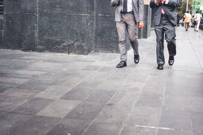 Low section of people walking on sidewalk in city