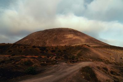 Scenic view of road by mountains against sky