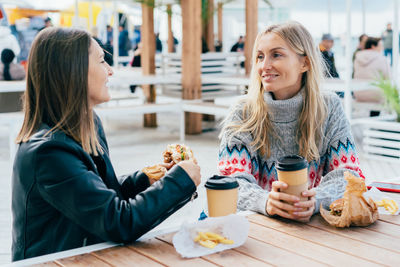 Portrait of smiling friends sitting on table