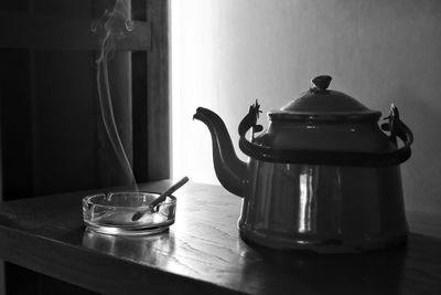 Close-up of burning cigarette in ashtray by kettle