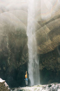Young active woman at a large mountain waterfall.