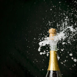 Champagne exploding from bottle against black background