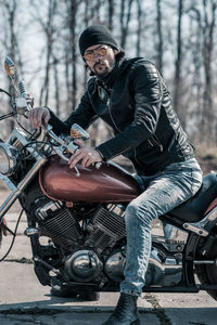 Mid adult man sitting on motorcycle in forest