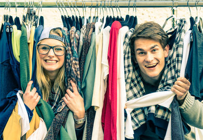 Portrait of smiling couple amidst clothes in store