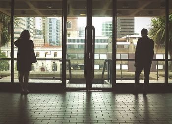 Rear view of silhouette people looking through window