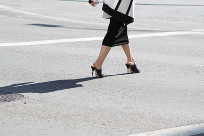 Low section of woman walking on road