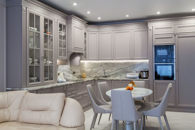 Modern beige and grey colored kitchen interior in classic style with dining table in luxury home