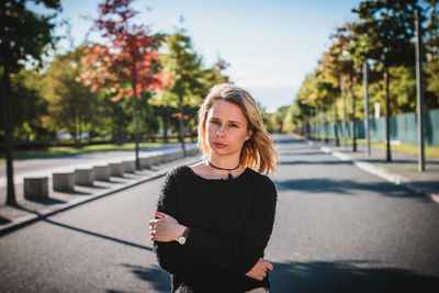 Beautiful young woman standing on road during sunny day