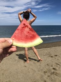 Midsection of woman on beach against sea against sky