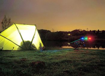 Illuminated tent on field against sky at night