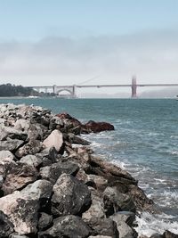 Rocks by sea with golden gate bridge in background
