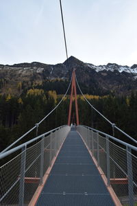 Footbridge over mountain against sky