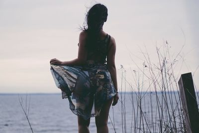 Rear view of young woman looking at sea