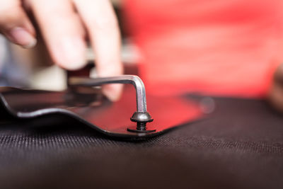 Cropped unrecognizable female hand turning screw while installing handle on chair at home