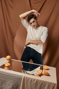 Man with hand raised against brown background