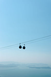 Low angle view of overhead cable cars against blue sky