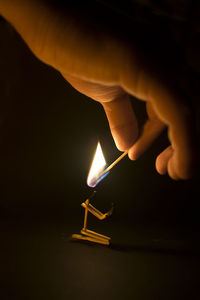 Person holding lit matchstick in dark