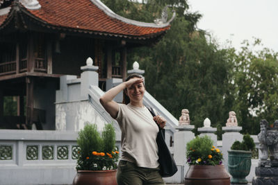 Happy young woman standing outdoors in the rain near asian pagoda